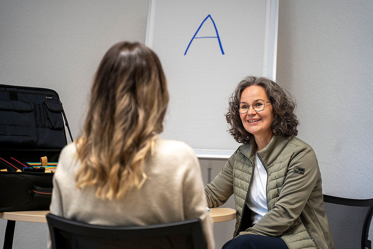 Coachinggespräch zwischen zwei Frauen vor Flipchart mit blauem A