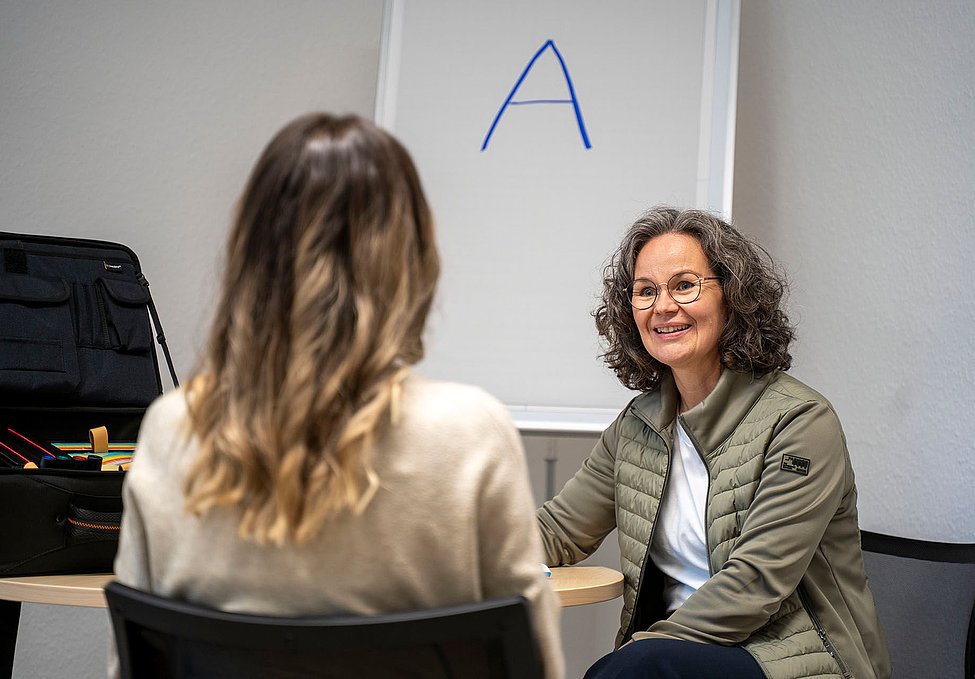 Coachinggespräch zwischen zwei Frauen vor Flipchart mit blauem A