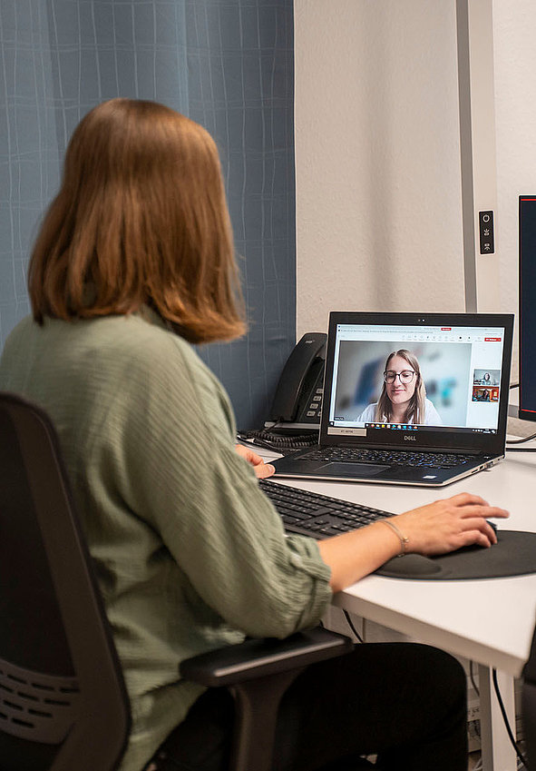Person am Schreibtisch beim E-Learning per Videokonferenz mit Zweitmonitor