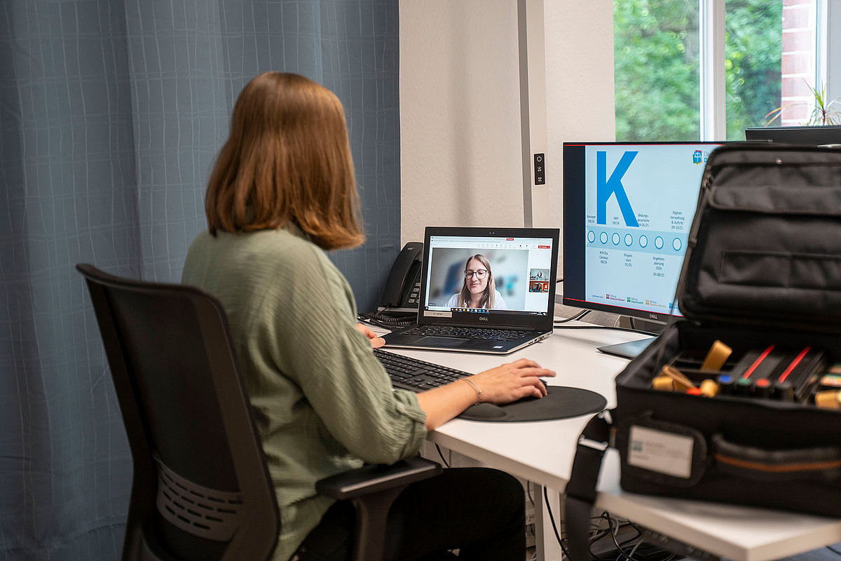 Person am Schreibtisch beim E-Learning per Videokonferenz mit Zweitmonitor