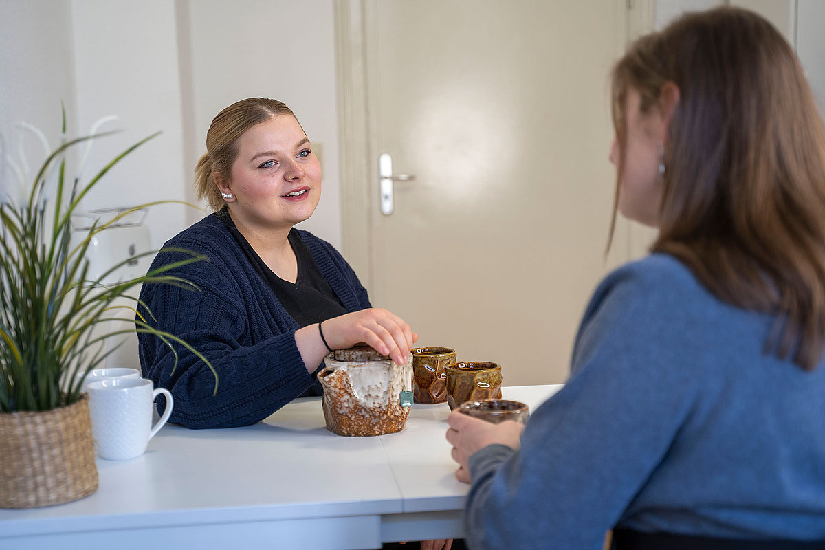 Zwei Personen im Gespräch bei Tee und Tassen