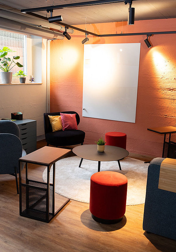 Gemütliche Lounge mit Monitor, Whiteboard, Sofa und Pflanzen